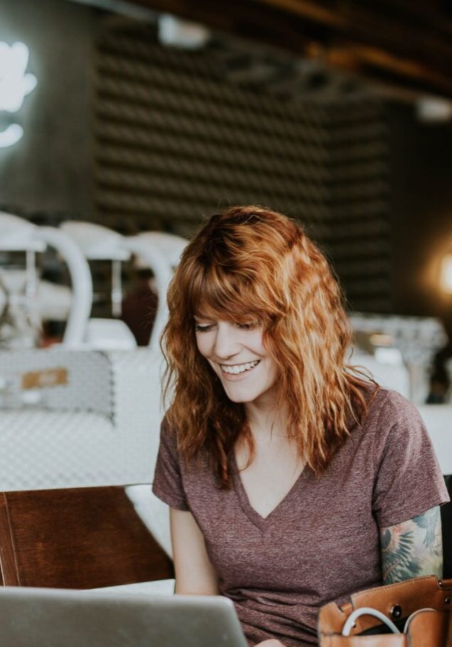 brooke-cagle-WHWYBmtn3_0-unsplash Woman smiling at laptop in cafe