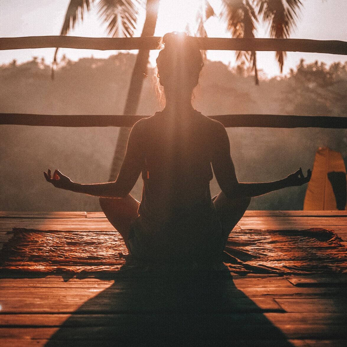 Silhouette of woman meditating outside in the sun