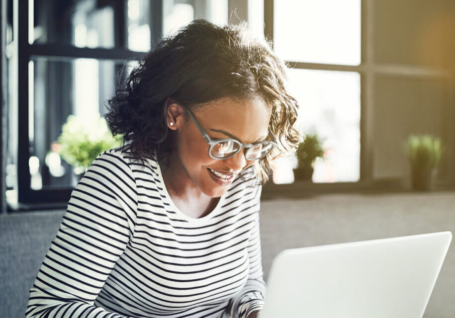 Woman smiling at laptop while in sun
