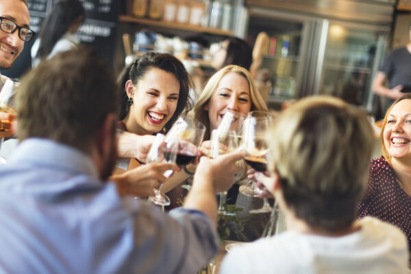 Group of people smiling and clinking wine glasses together