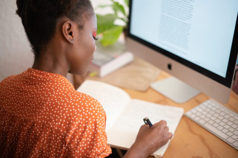 Woman at desktop writing in a journal